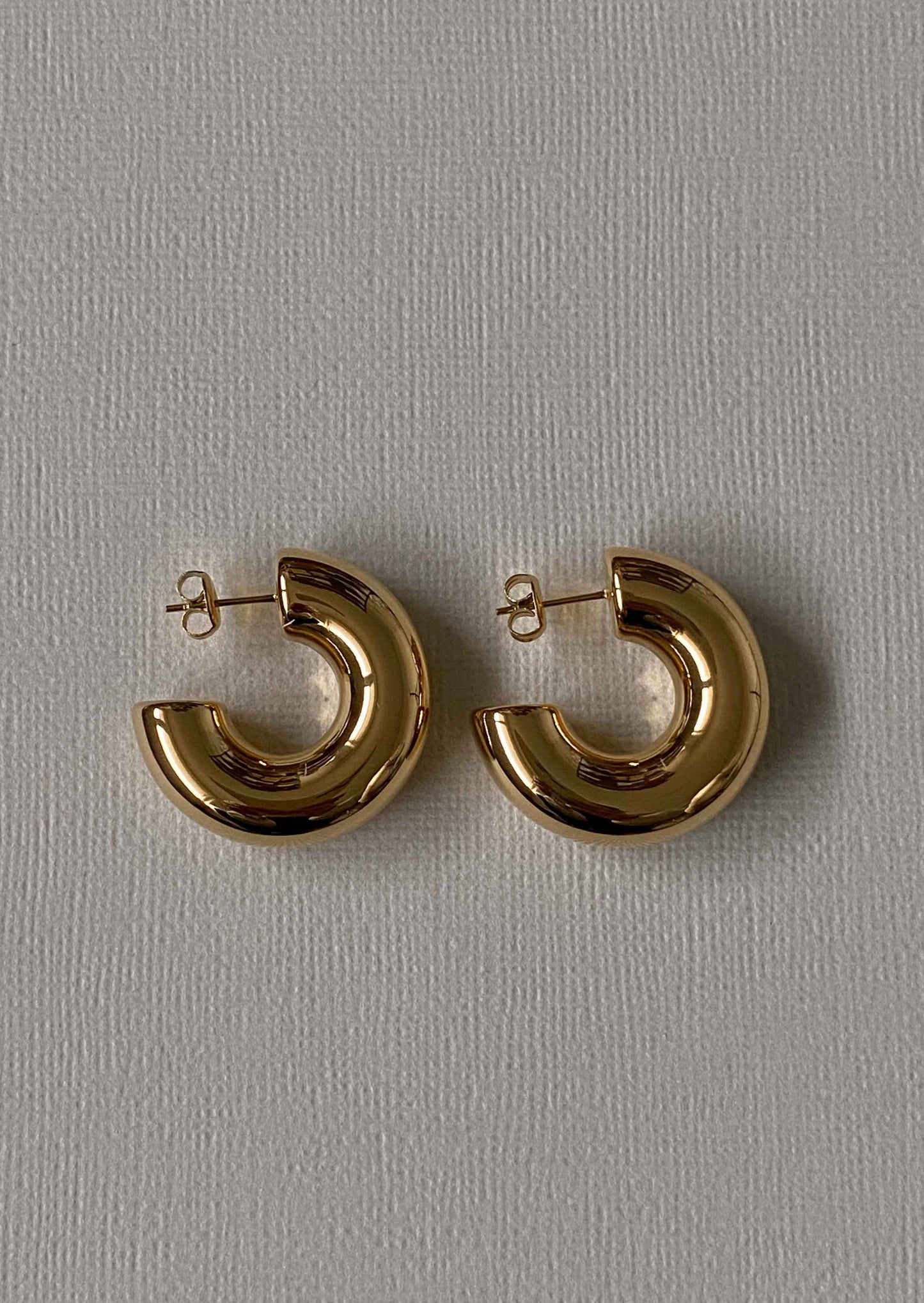 Gold hoop earrings on a gray background