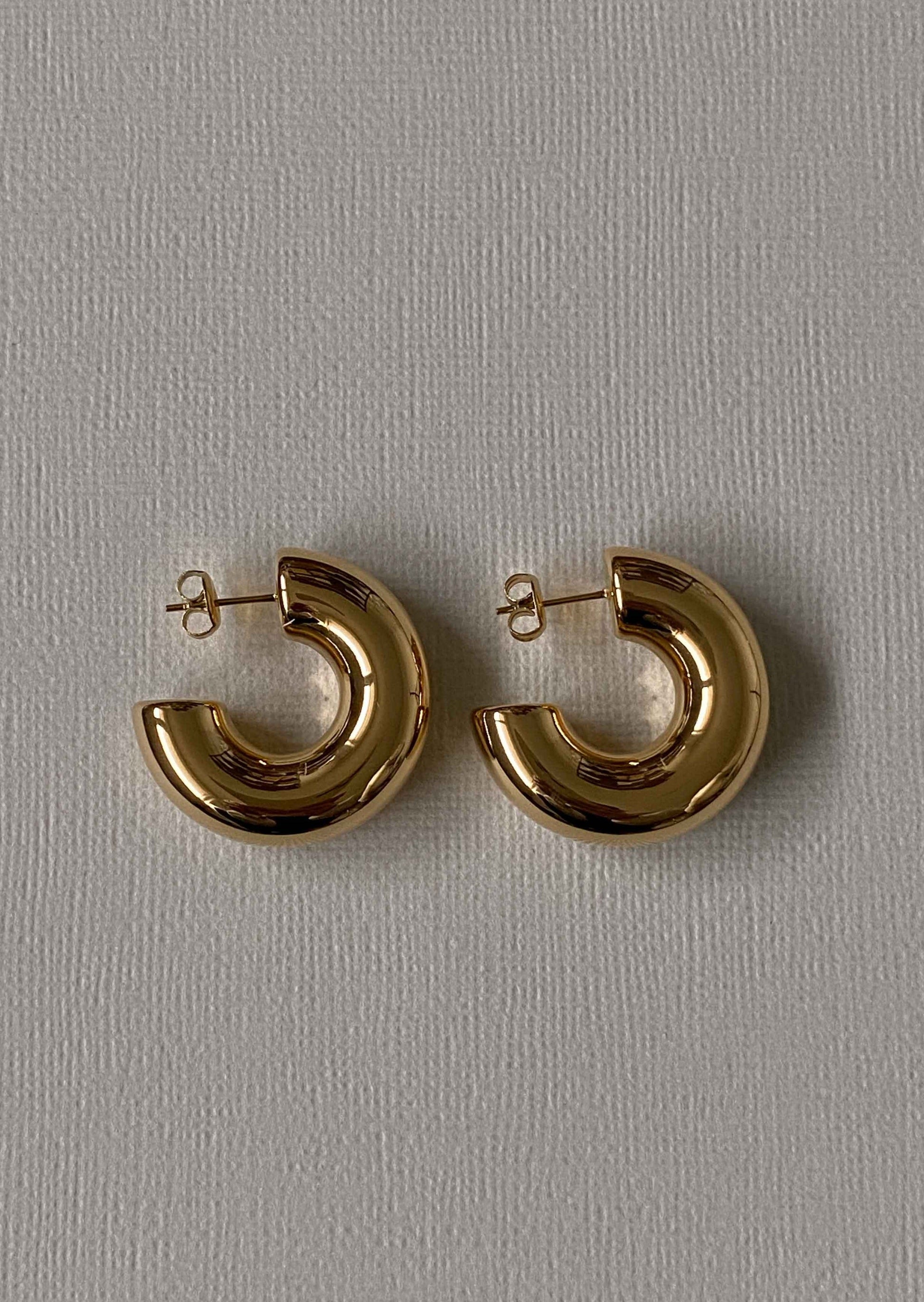 Gold hoop earrings on a gray background