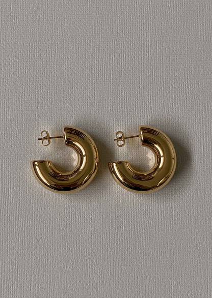 Gold hoop earrings on a gray background