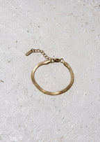 Gold bracelet on a light gray textured surface