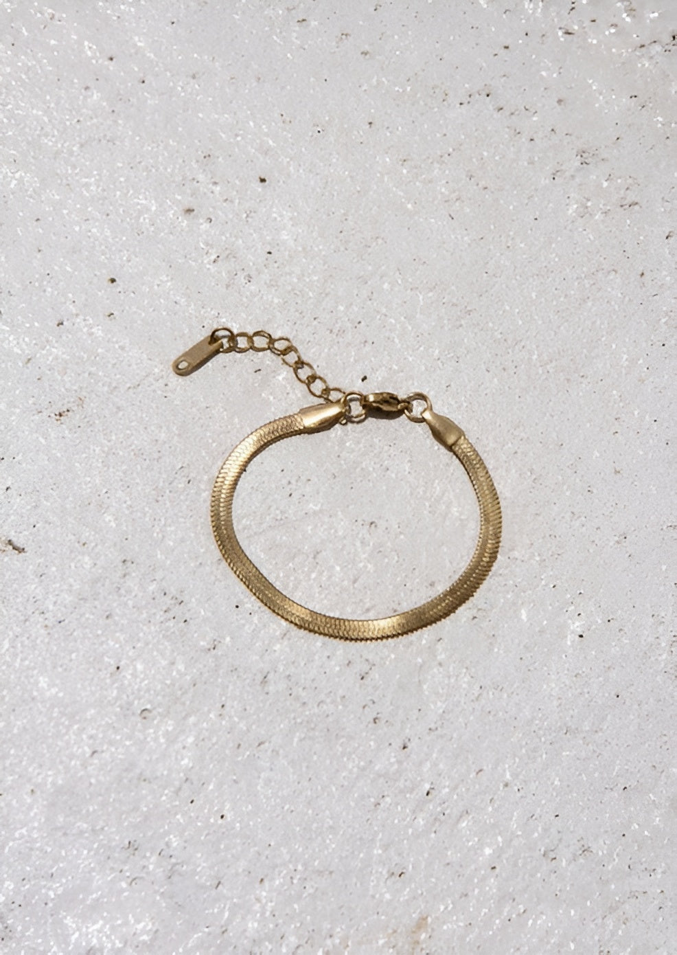 Gold bracelet on a light gray textured surface