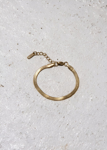Gold bracelet on a light gray textured surface