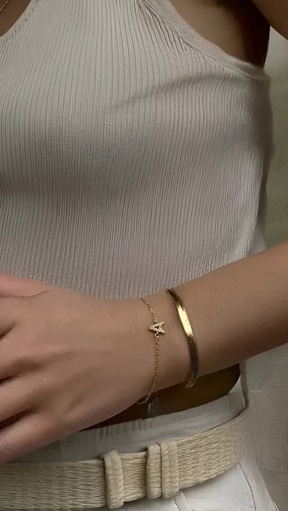 Close-up of a person wearing two gold bracelets on a neutral background