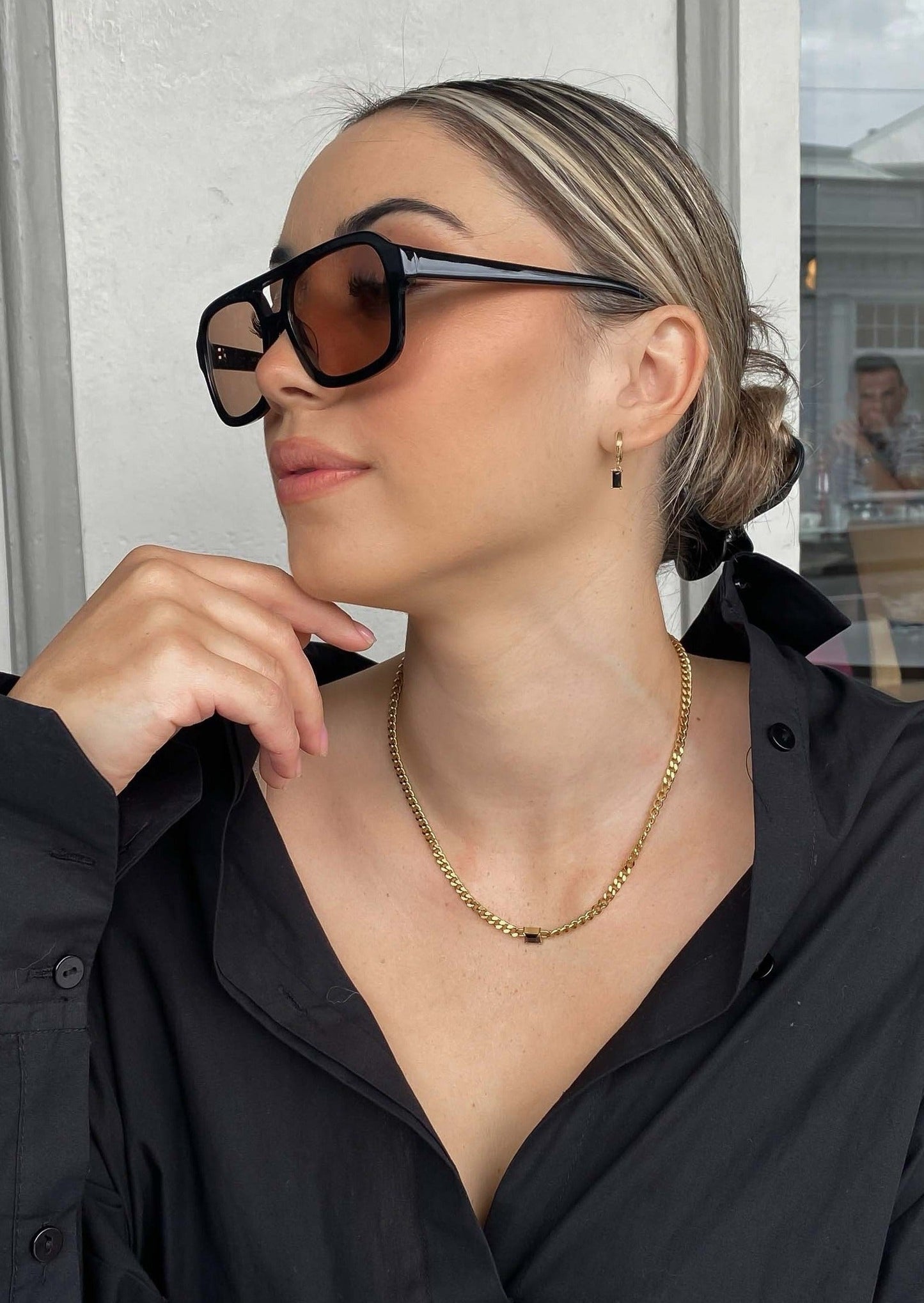 Woman wearing sunglasses and a black shirt indoors