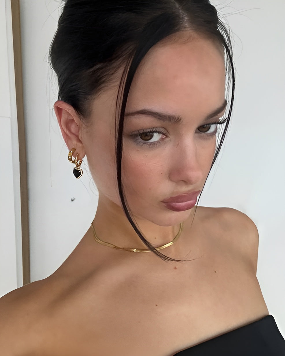 Close-up of a person wearing gold jewelry against a neutral background