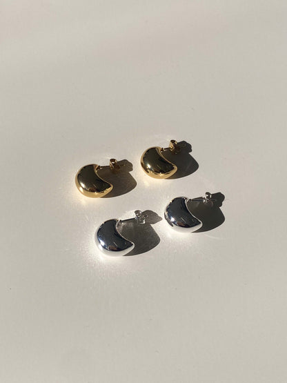 Two pairs of gold and silver earrings on a light gray background