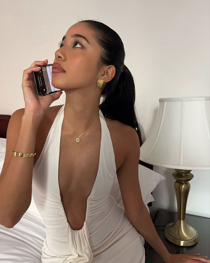 Woman in a white dress talking on a phone in a bedroom setting