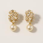 Pair of pearl earrings with gold accents on a beige background