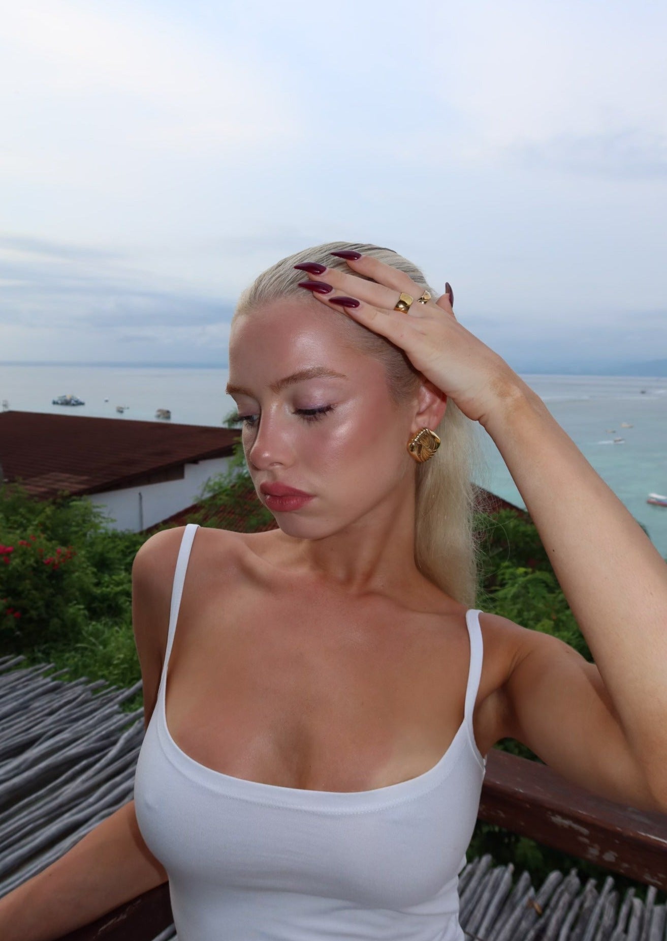Woman with blonde hair and a white top standing outdoors with a scenic background