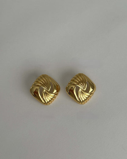 Pair of gold earrings on a light gray background
