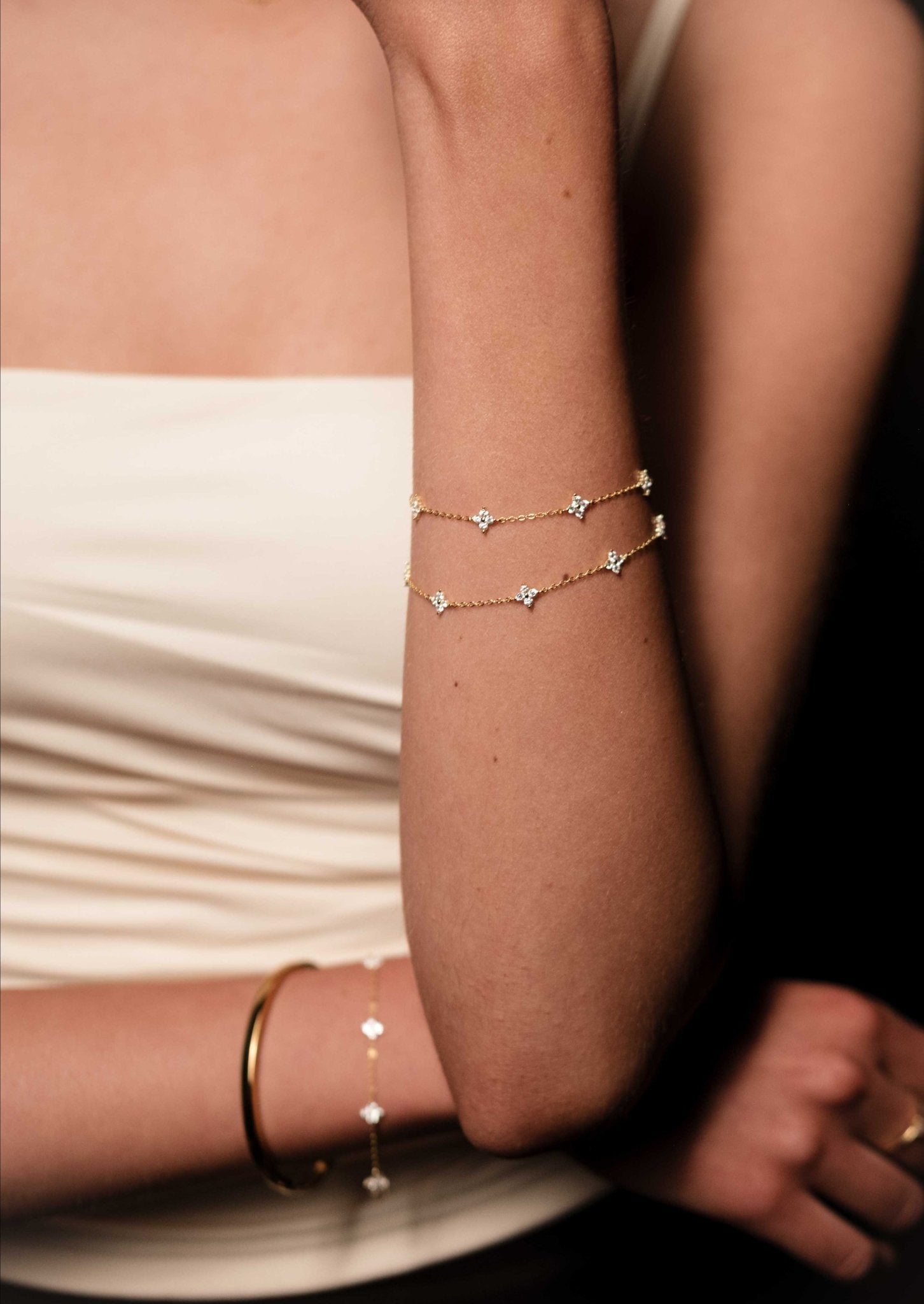 Close-up of a person's arm wearing gold bracelets with a blurred background