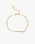 Gold double-chain bracelet with a rectangular diamond-studded bar and adjustable heart-shaped clasp. Elegant jewelry accessory.