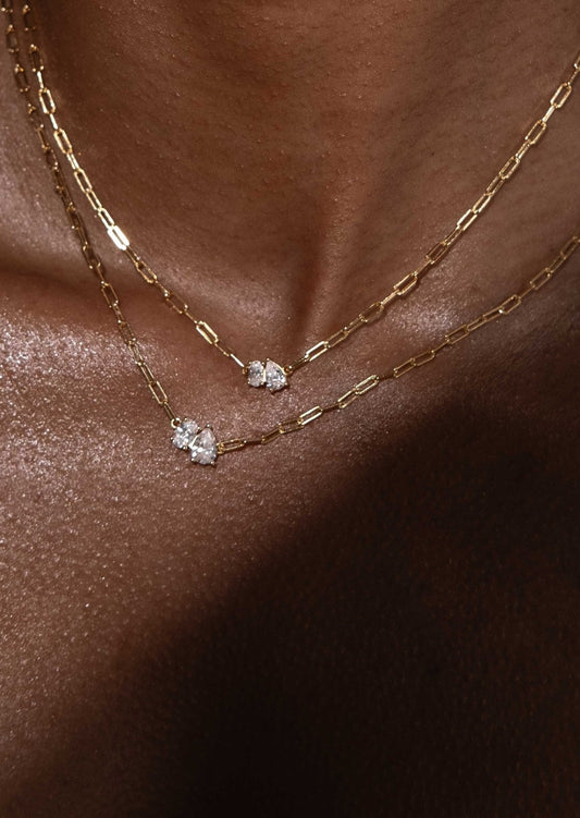 Gold chain necklaces with diamond pendants on dark skin, showcasing elegant jewelry design, luxury fashion accessories, and sparkling gemstones.