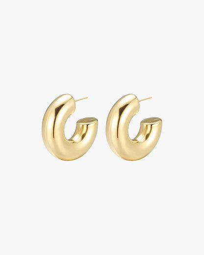 Gold hoop earrings with a chunky, modern design on a white background. Fashion jewelry, statement accessory, elegant style.