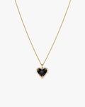 Gold chain necklace with a heart-shaped black gemstone pendant, surrounded by small clear crystals, on a white background. Elegant jewelry accessory.