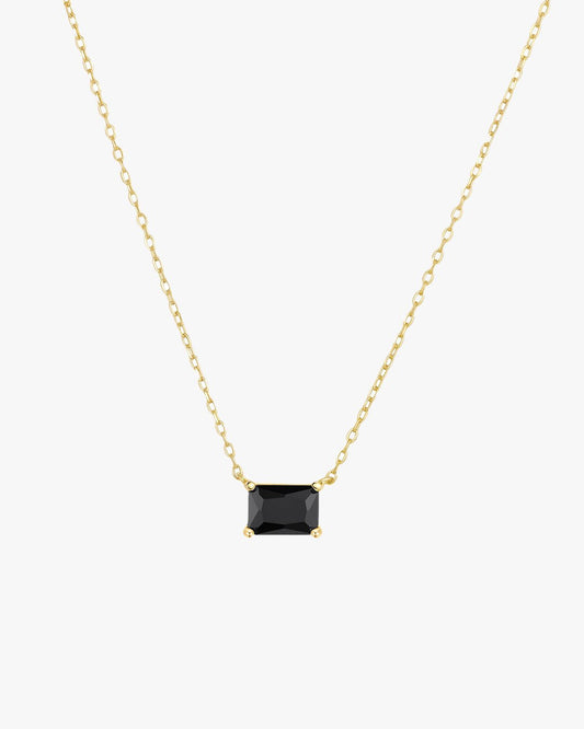 Gold chain necklace with a rectangular black gemstone pendant, minimalist jewelry design, elegant accessory for fashion-forward style.