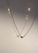 Gold necklace with a single sparkling diamond pendant casting a shadow, illuminated by soft light. Elegant jewelry, minimalist design, luxury accessory.