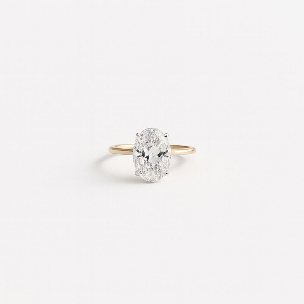 Oval diamond engagement ring with a gold band on a white background. Elegant solitaire design, perfect for proposals and weddings.