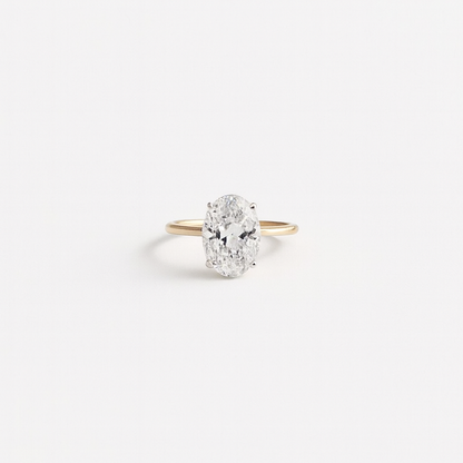 Oval diamond engagement ring with a gold band on a white background. Elegant solitaire design, perfect for proposals and weddings.