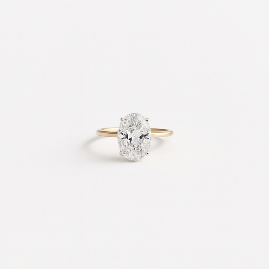 Oval diamond engagement ring with a gold band on a white background. Elegant solitaire design, perfect for proposals and weddings.