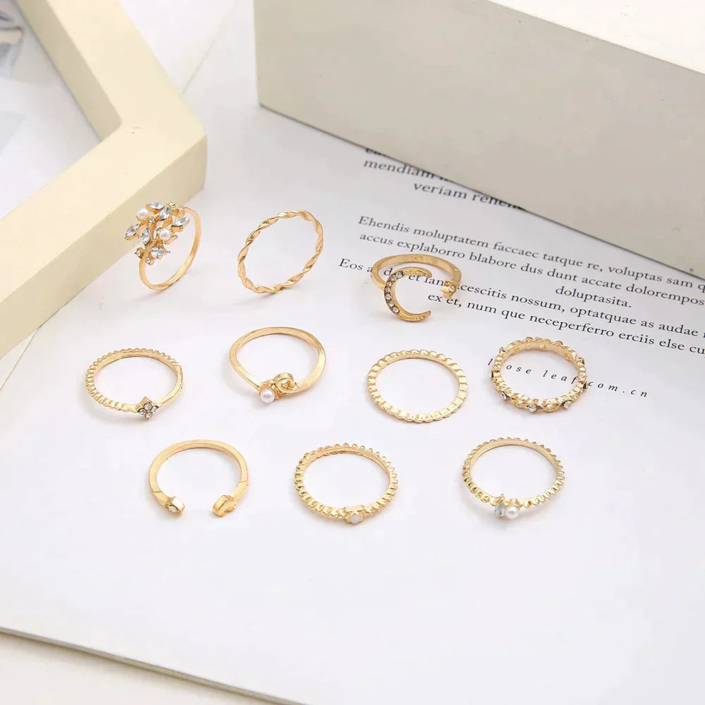 Gold stackable rings set with various designs, including twisted, beaded, and pearl accents, displayed on a white background. Elegant jewelry collection.