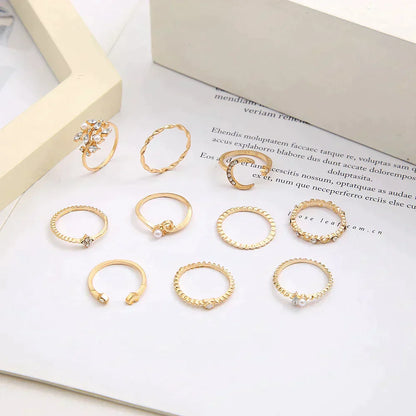 Gold stackable rings set with various designs, including twisted, beaded, and pearl accents, displayed on a white background. Elegant jewelry collection.