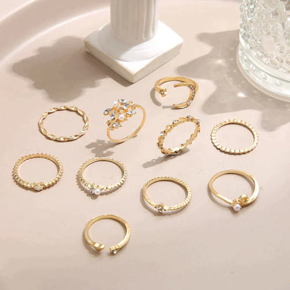Elegant gold rings set with pearl accents on a beige surface, featuring various intricate designs, perfect for fashion jewelry enthusiasts and gift ideas.