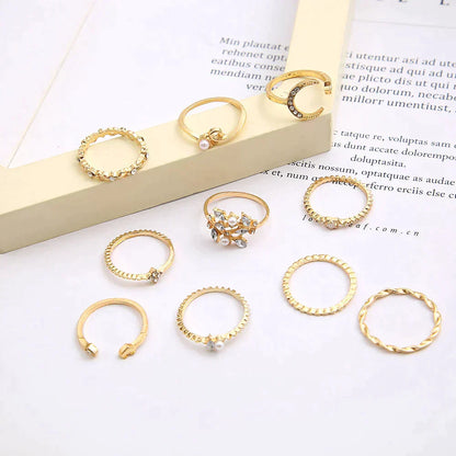 Gold rings set with pearls and crystals on a white background, featuring various designs including twisted and braided styles, perfect for fashion accessories.