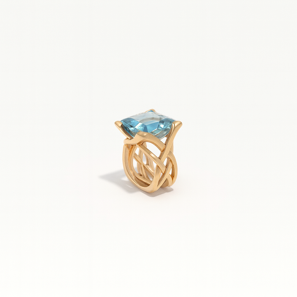 Gold ring with a large blue gemstone, featuring an intricate twisted band design. Elegant jewelry piece, perfect for luxury fashion and accessories.