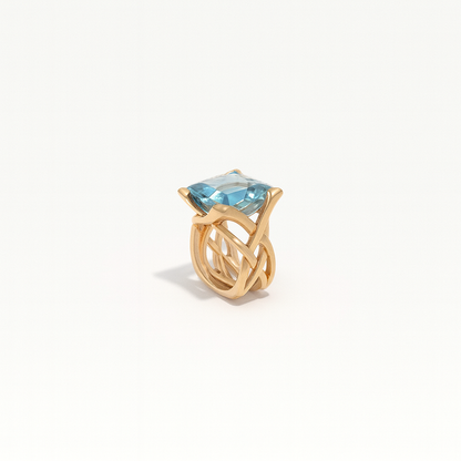 Gold ring with a large blue gemstone, featuring an intricate twisted band design. Elegant jewelry piece, perfect for luxury fashion and accessories.