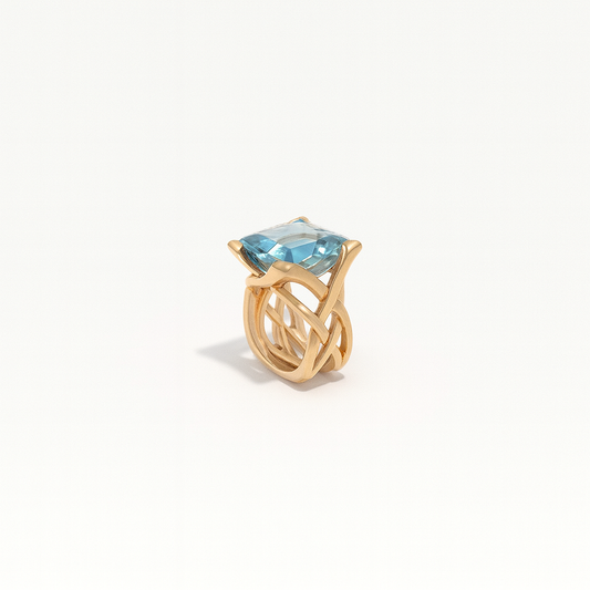 Gold ring with a large blue gemstone, featuring an intricate twisted band design. Elegant jewelry piece, perfect for luxury fashion and accessories.