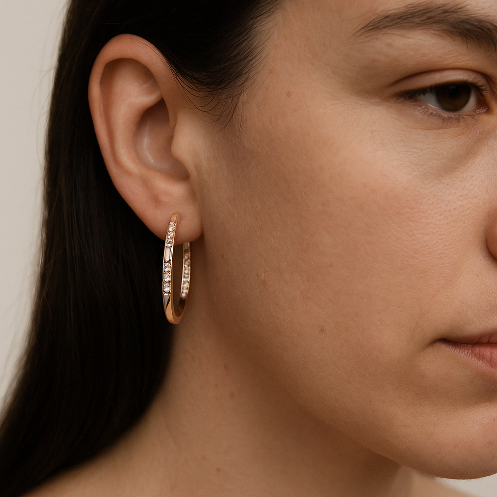 Close-up of a person wearing gold hoop earrings with a neutral background