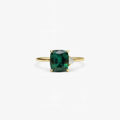 Gold ring with a cushion-cut green gemstone and a small diamond accent, elegant jewelry design, perfect for engagement or special occasions.