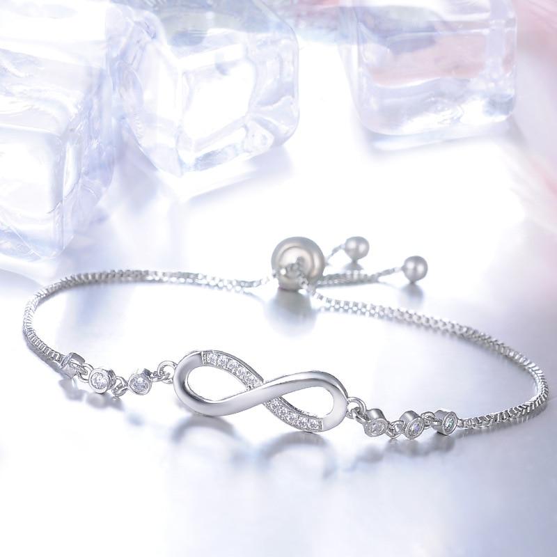 Elegant silver infinity bracelet with sparkling cubic zirconia stones, adjustable chain, and ice cube background. Perfect for fashion and jewelry lovers.