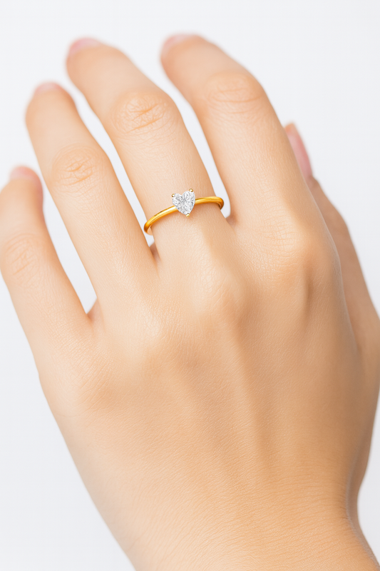 Hand wearing a gold ring with a heart-shaped diamond, showcasing elegant jewelry design, perfect for engagement or anniversary gifts.