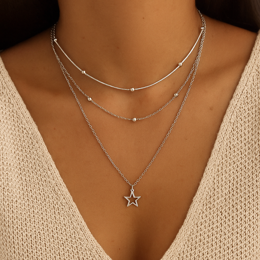 Silver star necklace worn by a person with a beige sweater