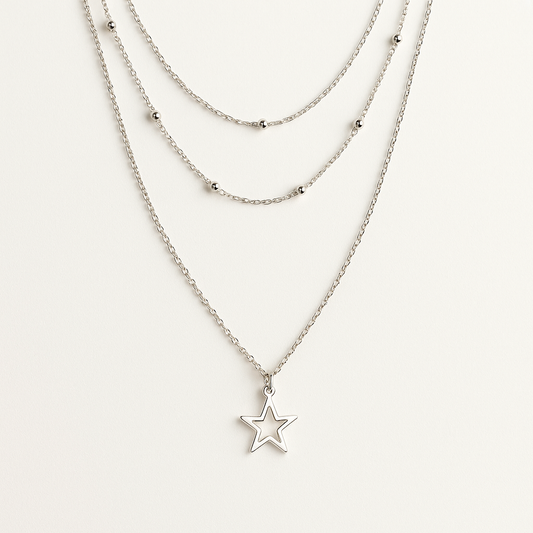 Layered silver necklaces with star pendants on a white background