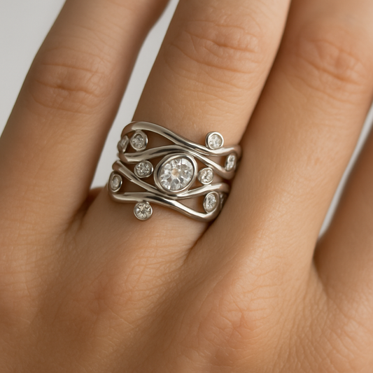 Silver ring with diamonds on a finger against a neutral background