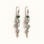Silver earrings with green gemstones on a white background