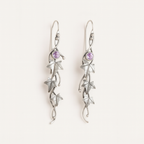 Silver earrings with star designs and purple gemstones on a white background
