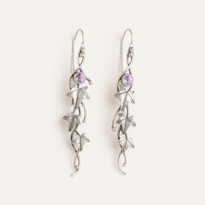 Silver earrings with star designs and purple gemstones on a white background