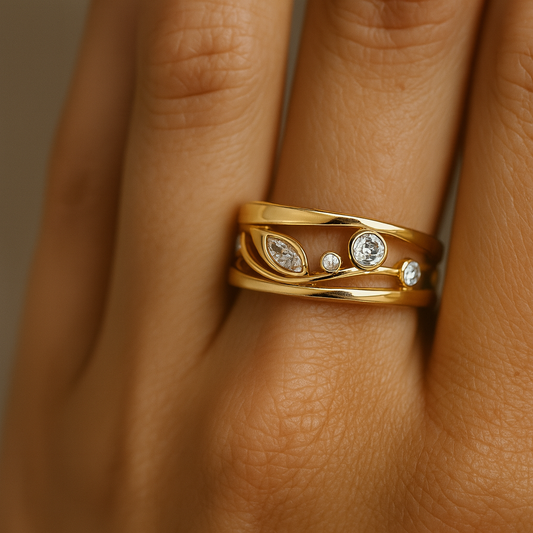 Gold ring with diamonds on a person's finger against a neutral background