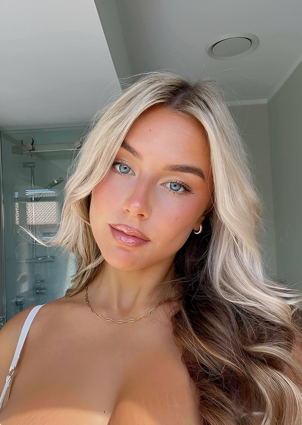 Woman with blonde hair and blue eyes in a bathroom setting