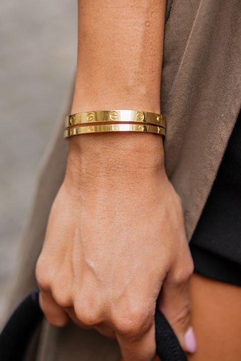 Gold bracelet on a wrist with a neutral background