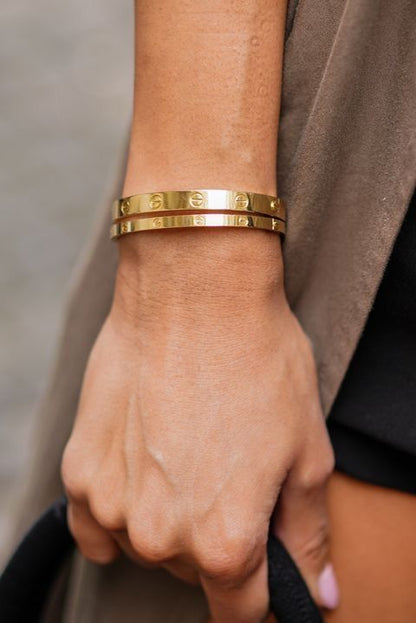 Gold bracelet on a wrist with a neutral background