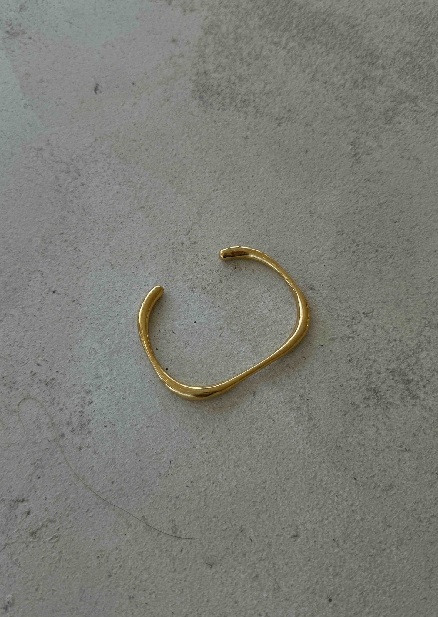 Gold bracelet on a gray surface