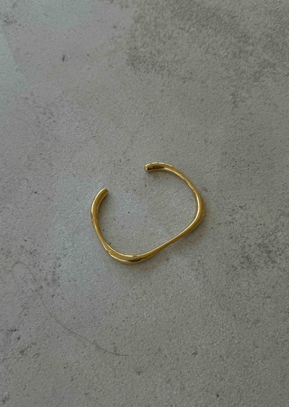 Gold bracelet on a gray surface