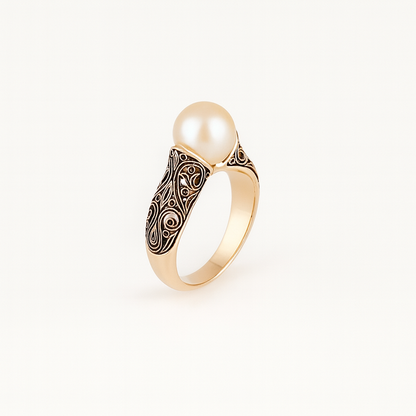 Gold ring with intricate filigree design featuring a large, lustrous pearl centerpiece. Elegant jewelry, luxury accessory, sophisticated style.