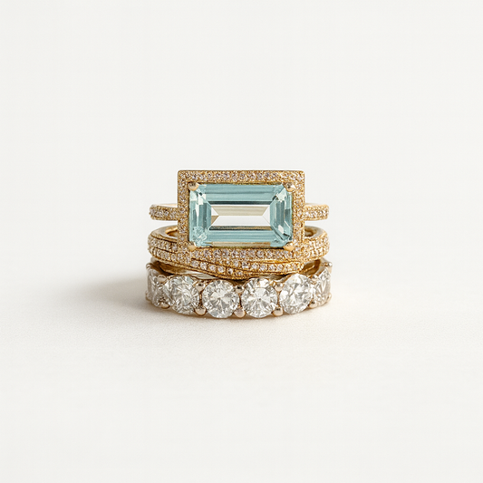 Set of three gold rings with gemstones on a light gray background