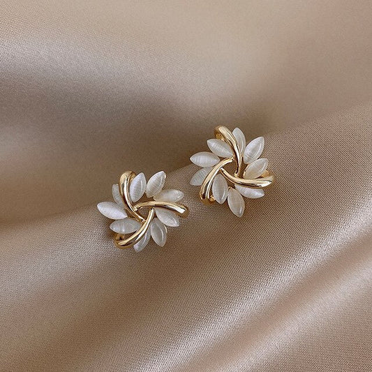 Elegant gold and pearl flower earrings on satin fabric, showcasing luxury jewelry design, perfect for fashion accessories and style enthusiasts.